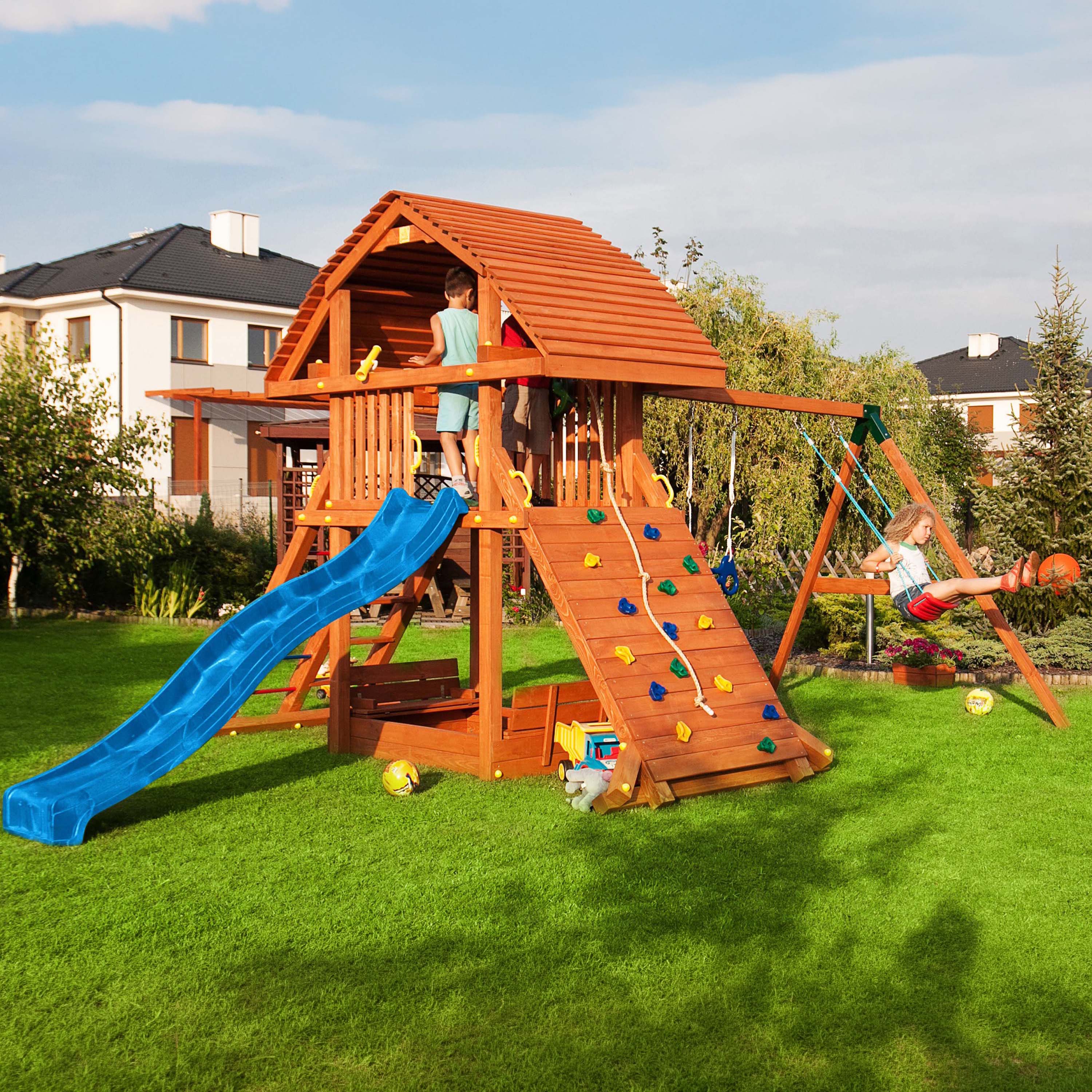 Drewniany plac zabaw z domkiem zjeżdżalnią i huśtawkami w ogrodzie dzieci podczas zabawy
