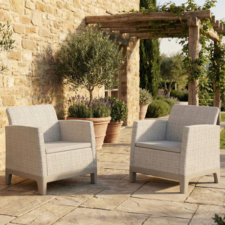 Dwa fotele ogrodowe Scandi Forma Duo w kolorze Pebble Grey-Soft Beige stojące na słonecznym tarasie przy kamiennej ścianie