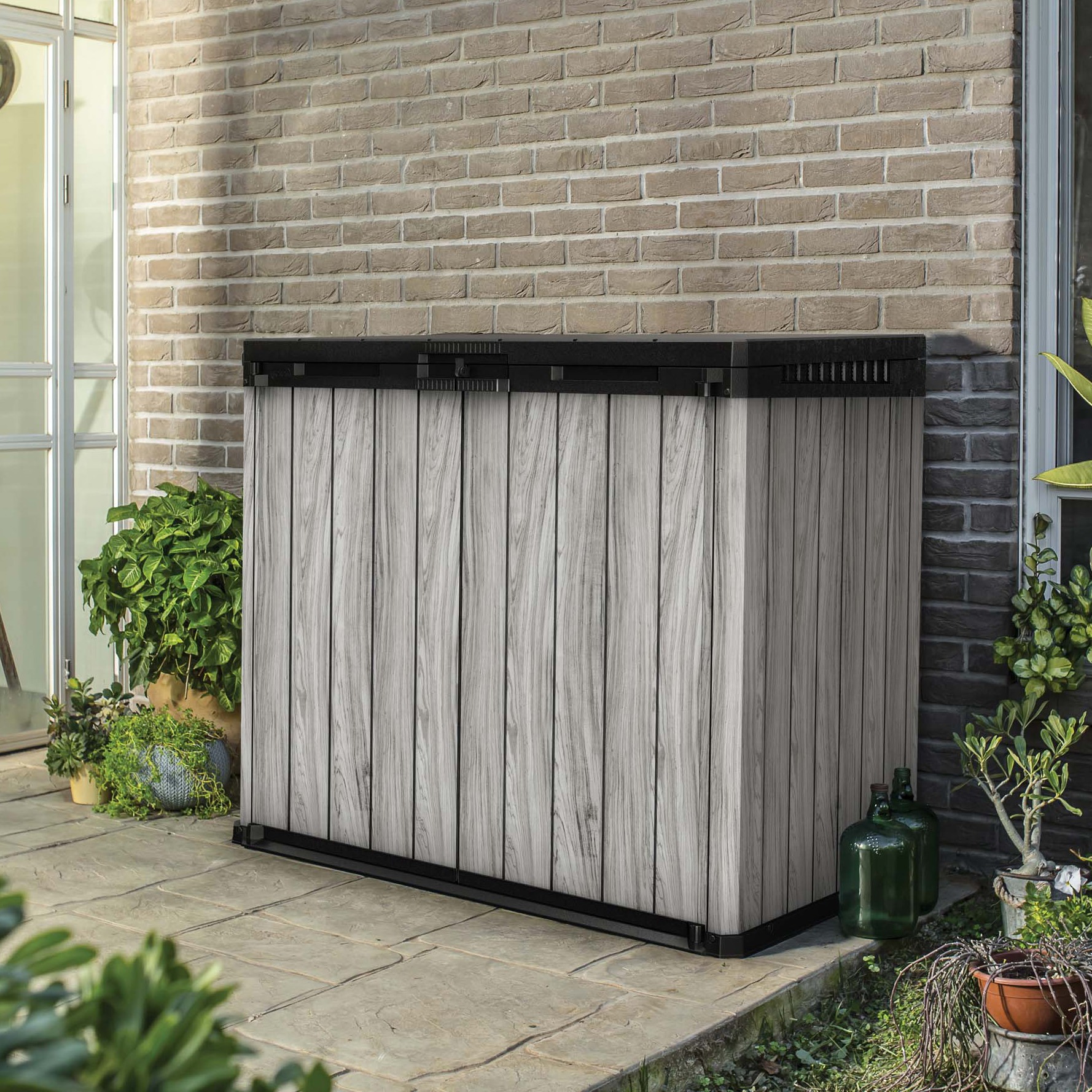 Organizer do ogrodu Keter SIO Darwin 1150L w kolorze Storm Grey w aranżacji tarasowej przy ceglanej ścianie