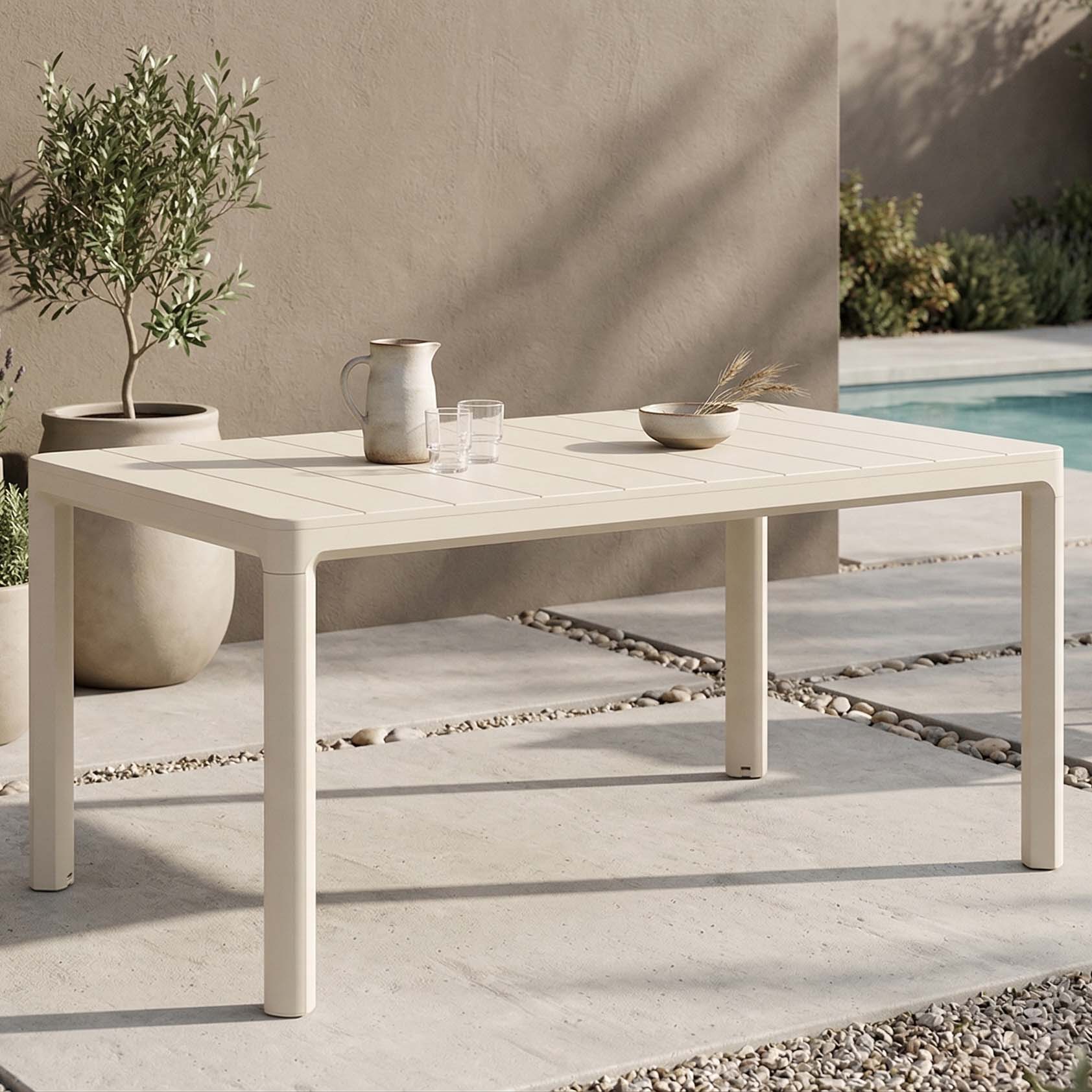 Beżowy stół ogrodowy Keter SCANDI DINING w słońcu na tarasie z ozdobną misą i dzbankiem