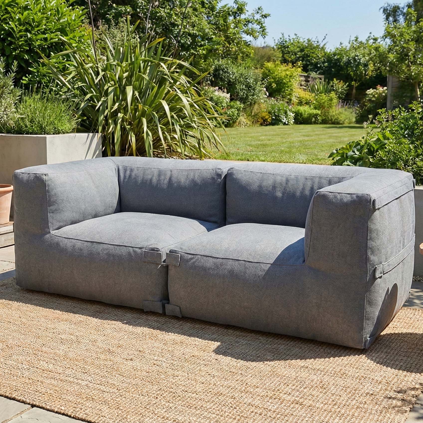 Szara sofa ogrodowa modułowa ustawiona w nowoczesnym ogrodzie na tarasie

