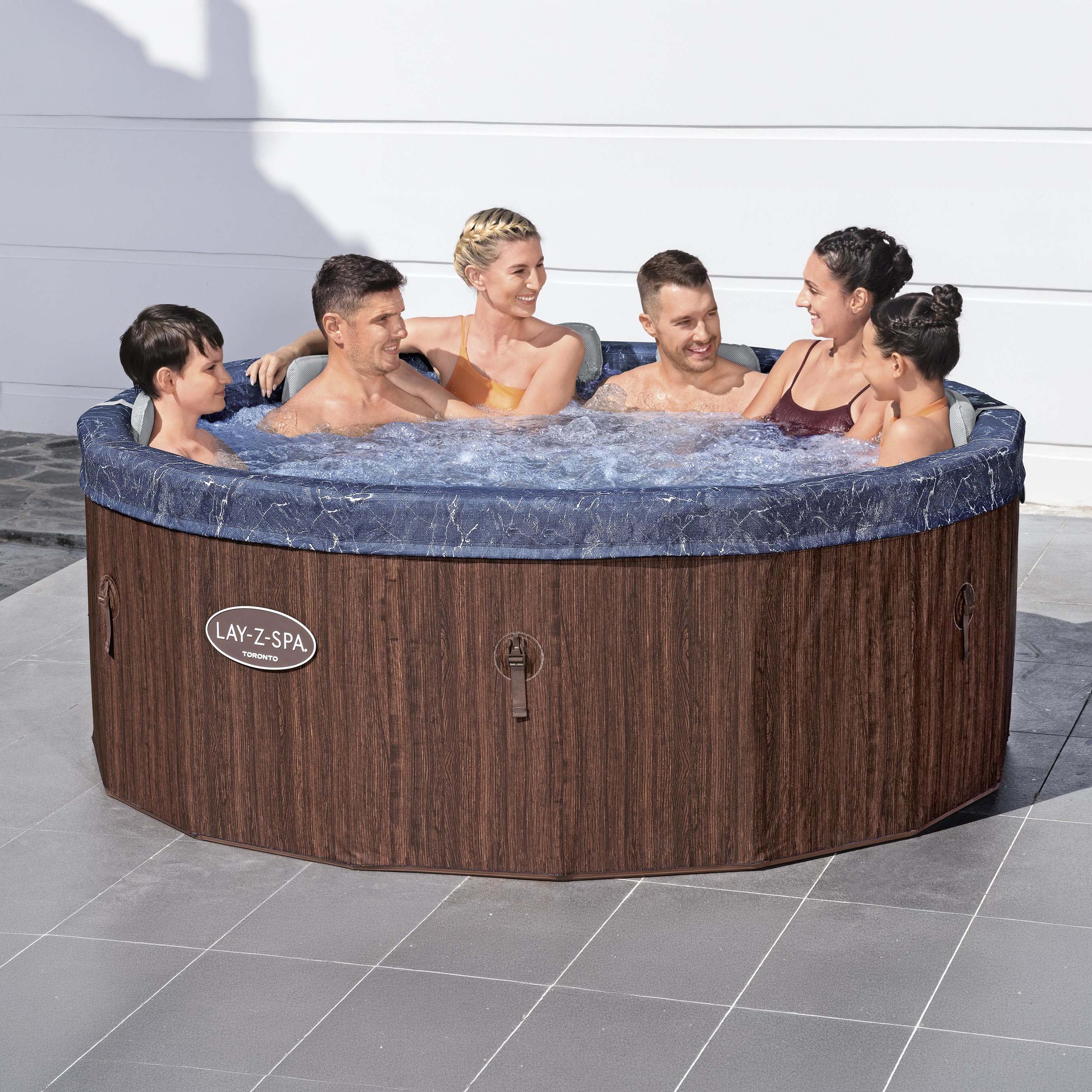 Wanna z hydromasażem LAY-Z-SPA TORONTO SMART AIRJET BROWN WOOD ROUNDE z sześcioma osobami relaksującymi się na zewnątrz