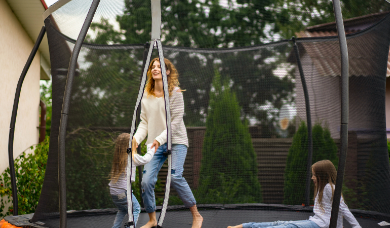 kobieta bawiąca się z córkami na trampolinie