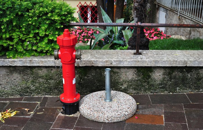 betonowa podstawa pod parasol ustawiona obok czerwonego hydrantu w ogrodzie